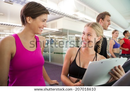Trainer talking to her client on the treadmill at the gym