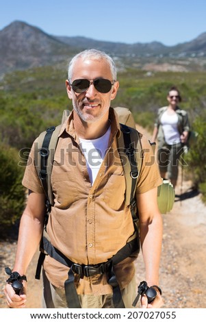 Happy hiking couple walking on mountain trail on a sunny day