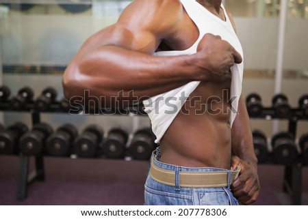 Close-up mid section of a muscular man standing in gym