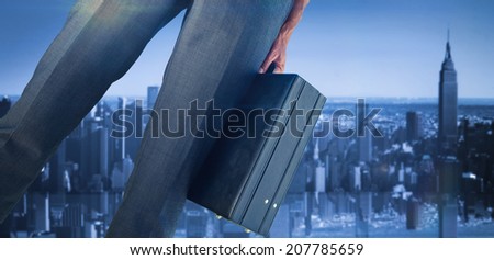 Businessman holding briefcase against mirror image of city skyline