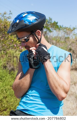 Fit cyclist fixing strap on helmet on a sunny day