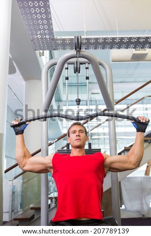 Strong man using weights machine for arms at the gym