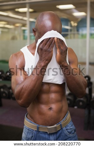 Muscular man wiping sweat after workout in gym