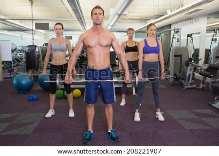 Fitness class lifting barbells together at the gym