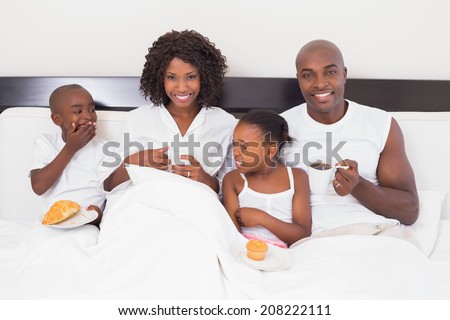 Happy family having breakfast in bed at home in the bedroom