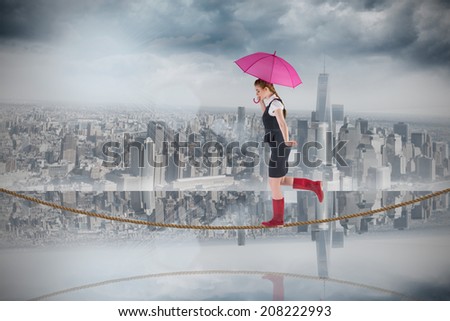 Pretty redhead businesswoman holding umbrella on tightrope against room with large window looking on city