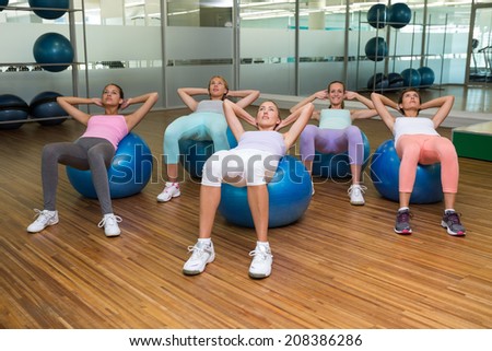 Fitness class doing sit ups on exercise balls in studio at the gym