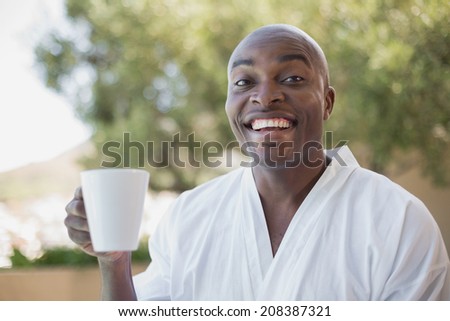 Handsome man in bathrobe having coffee outside on a sunny day