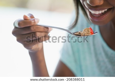 Smiling woman eating cereal outside on a sunny day