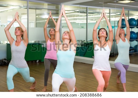 Yoga class in warrior pose in fitness studio at the leisure center