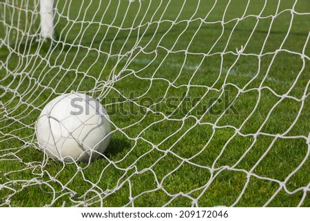Football at the back of the net on a clear day