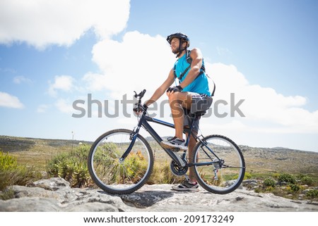 Fit man cycling on rocky terrain on a sunny day