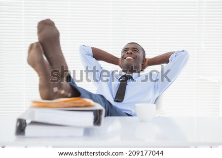 Relaxed businessman sitting in his chair with feet up in his office