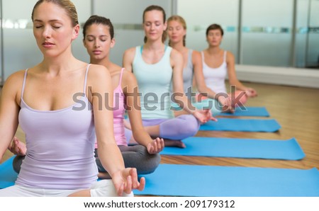 Yoga class in lotus pose in fitness studio at the leisure center