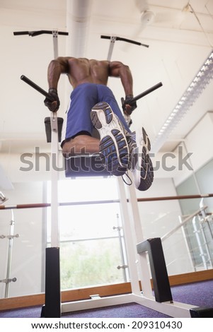 Low angle view of a male body builder doing pull ups at the gym