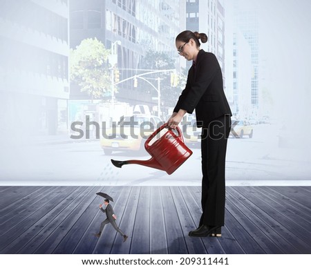 Businesswoman watering tiny businessman against urban projection on wall