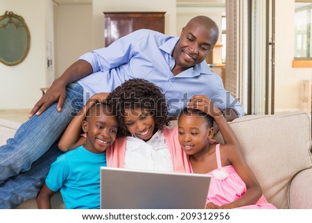 Happy family relaxing on the couch using laptop at home in the living room