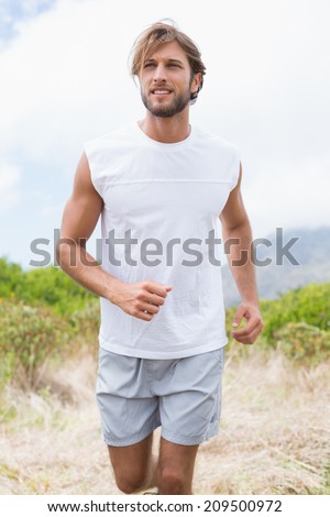Attractive man jogging on mountain trail on a sunny day