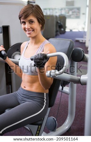 Healthy happy brunette using weights machine for arms at the gym