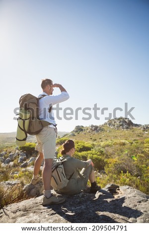 Hiking couple looking out over mountain terrain on a sunny day