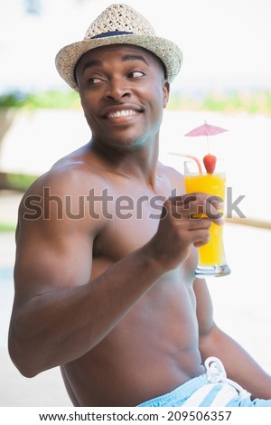Smiling man in swimming trunks holding a cocktail on a sunny day