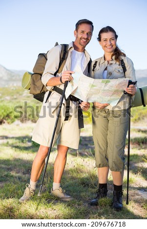 Hiking couple consulting the map in the countryside on a sunny day