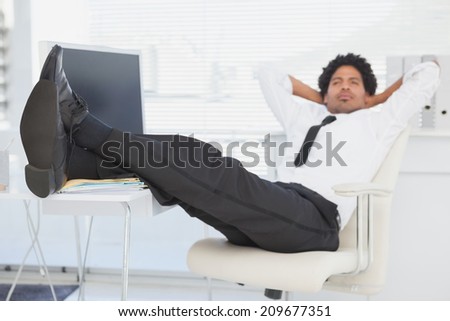 Businessman relaxing in his swivel chair with feet up in his office