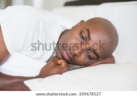 Unhappy man lying in bed at home in the bedroom