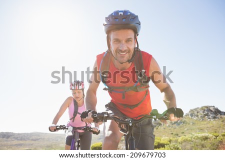 Fit cyclist couple riding together on mountain trail on a sunny day