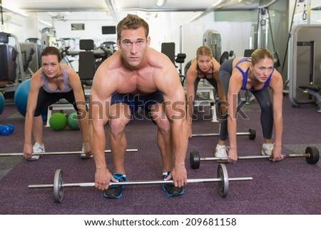 Fitness class lifting barbells together at the gym