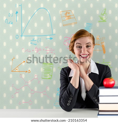 Excited redhead teacher sitting at desk against red apple on pile of books