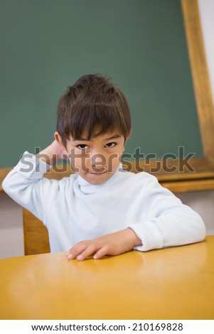 Cute pupil sitting at desk in classroom at the elementary school