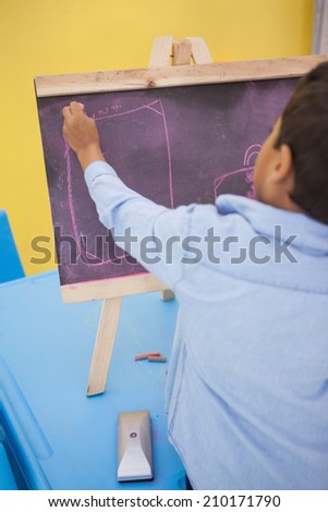 Cute little boy drawing on chalkboard at the nursery school