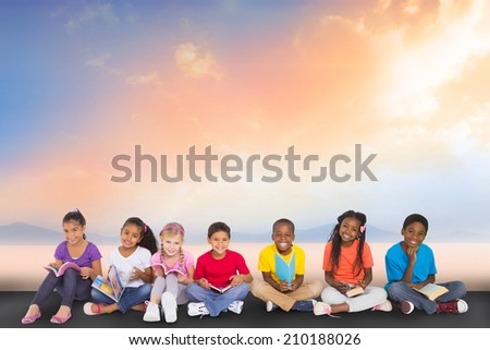 Cute pupils smiling at camera with books against desert landscape