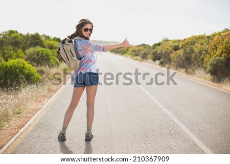 Portrait of a pretty young woman hitchhiking on countryside road