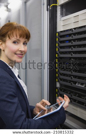 Pretty technician using tablet pc while working on servers in large data center