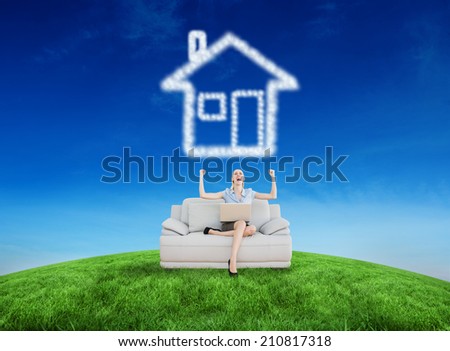 Cheering beautiful businesswoman sitting on couch against green hill under blue sky