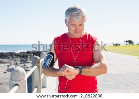 Fit mature man checking the time on the pier on a sunny day