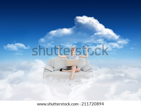 Cheering beautiful businesswoman sitting on couch against bright blue sky with clouds