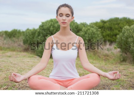 Healthy and beautiful woman sitting in lotus position on countryside landscape