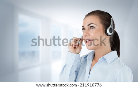 Call center agent looking upwards while talking against bright white hall with columns