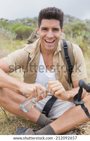 Portrait of a cheerful hiking man sitting on mountain terrain