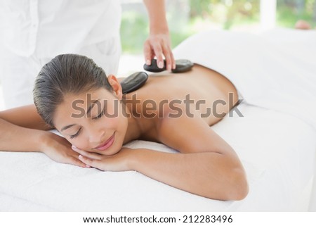 Beautiful brunette enjoying a hot stone massage at the health spa