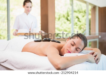 Side view of a beautiful young woman receiving stone massage at health farm