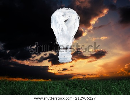Cloud light bulb against green grass under dark blue and orange sky