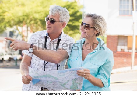 Happy tourist couple using map in the city on a sunny day