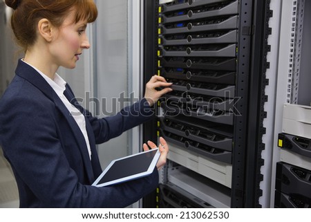 Pretty technician using tablet pc while working on servers in large data center
