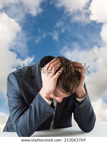 Businessman with head in hands against blue sky with white clouds