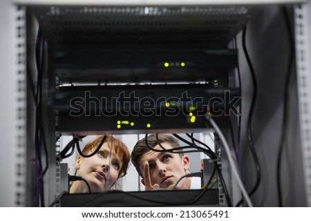 Team of technicians talking and looking at server in large data center