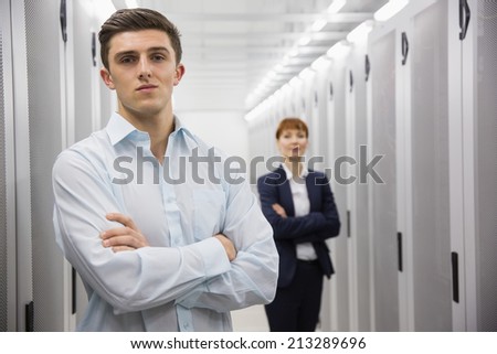 Team of computer technicians looking at camera in large data center